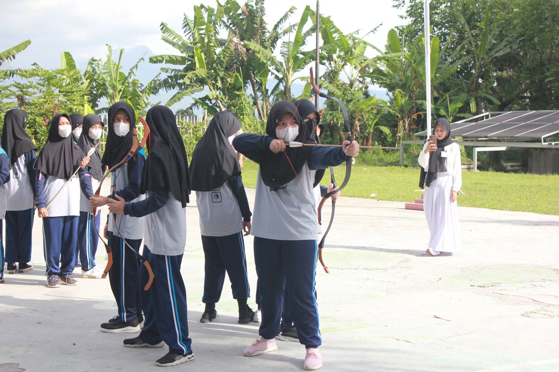 Siswa berlatih panahan di area terbuka sekolah.